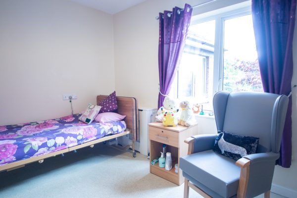 bedroom with purple curtains and blue arm chair